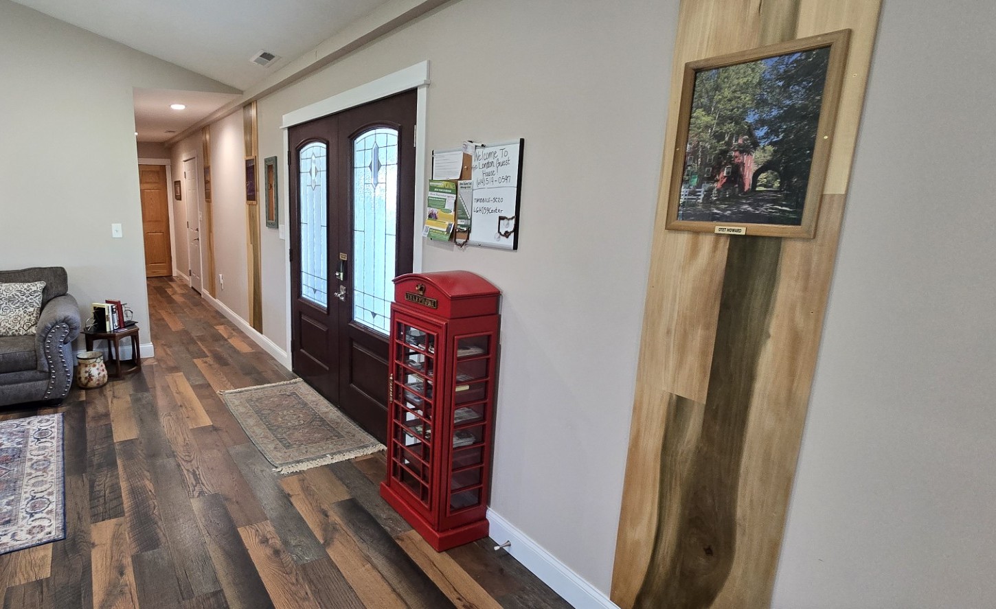 20260521_175040edit - London Guest House Cozy entry hall with dark double front doors, a red post box against the wall, and a wood floor leading to a living area on the left.